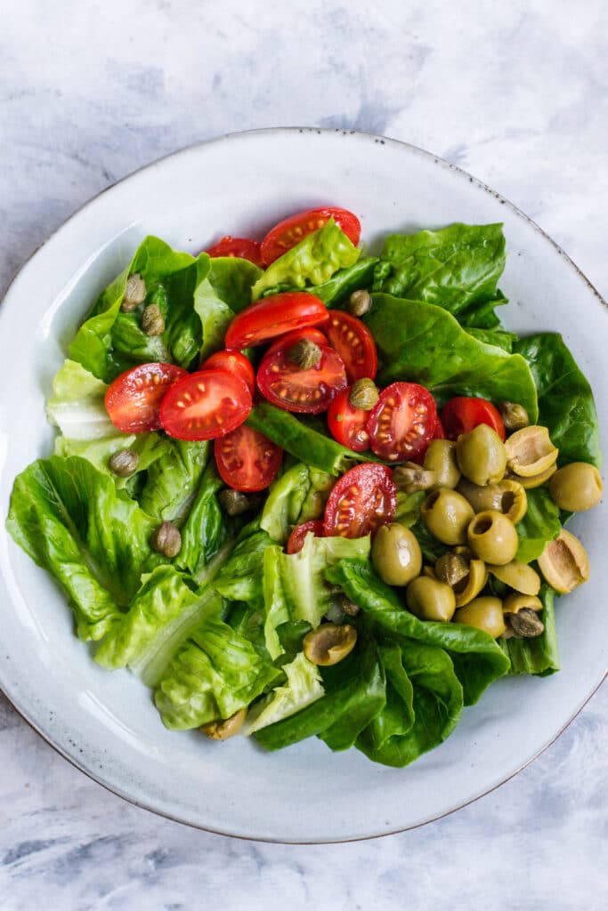 Lettuce, olives, tomatoes and capers in a bowl
