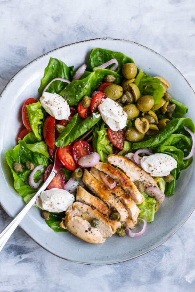 Keto grilled chicken salad in a bowl with dollops of cream cheese on top