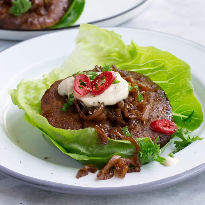 Turkey burgers wrapped in lettuce leaves served with sauce and caramelised onions