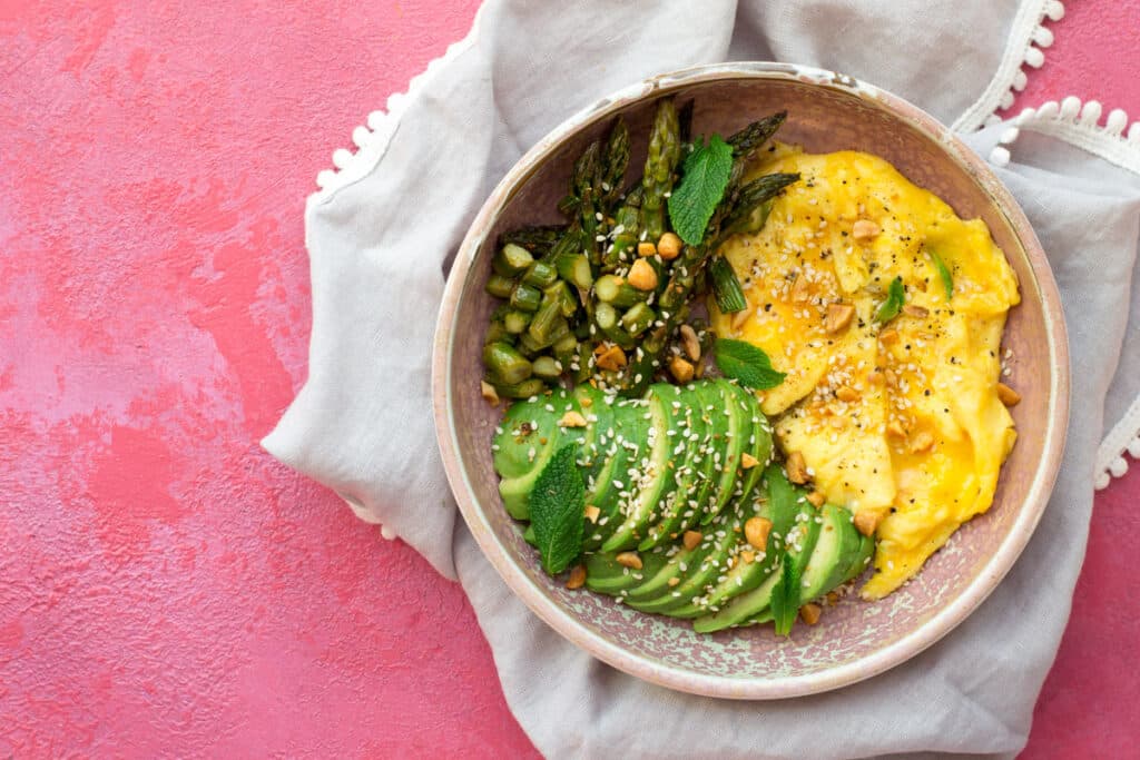 Eggs, avocado and asparagus in a pink bowl