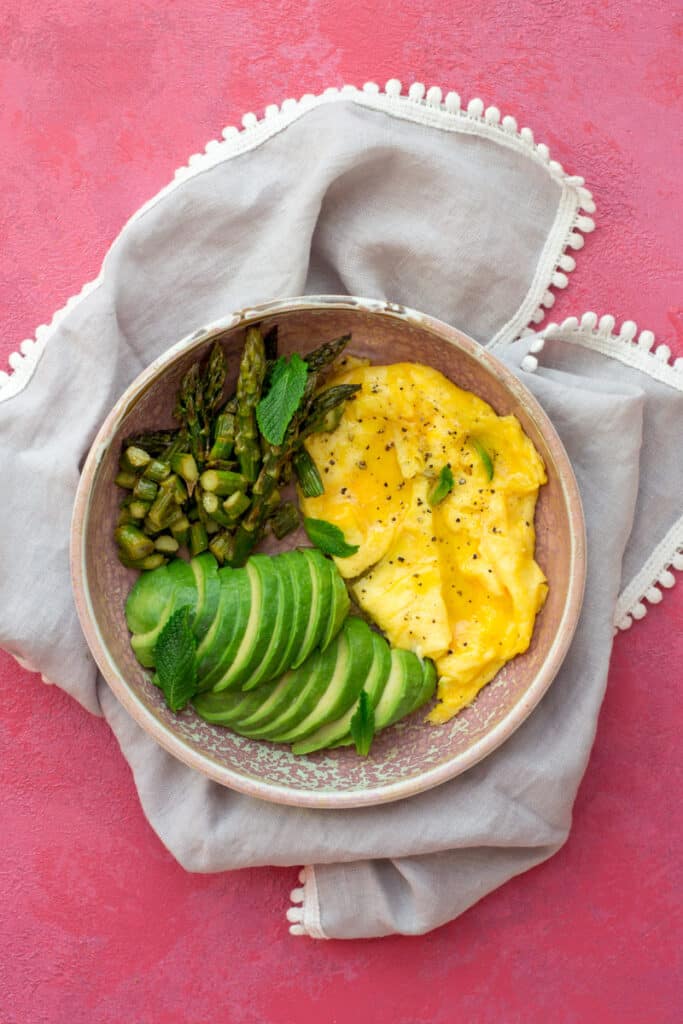 Scrambled eggs, avocado and asparagus in a bowl