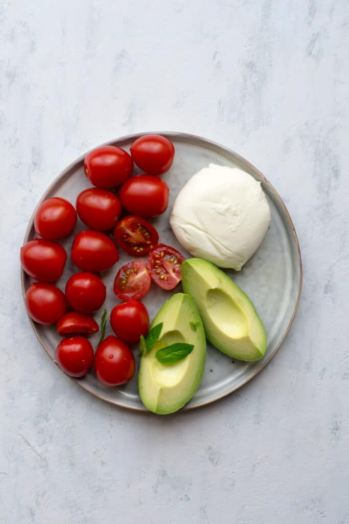 Ingredients for Caprese salad with avocado on a plate